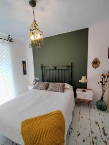 Un dormitorio con una gran cama blanca y una lámpara de araña. en Covaleda naturazleza y relax, en Covaleda