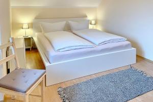 un letto bianco in una stanza con sedia di Ferienhaus Kiefernwäldchen a Byhlen