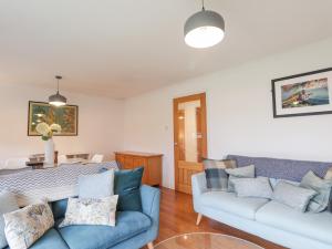 a living room with two blue couches and a table at Pebble Cottage in Portree