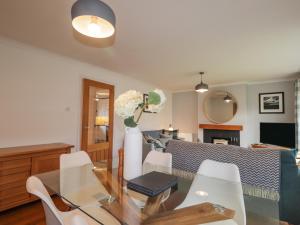 een woonkamer met een glazen tafel en witte stoelen bij Pebble Cottage in Portree