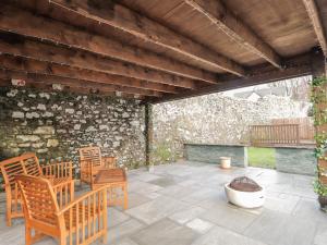 a patio with wooden chairs and a stone wall at Pebble Cottage in Portree