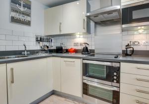 a kitchen with white cabinets and a stove top oven at Zephyr in Fowey