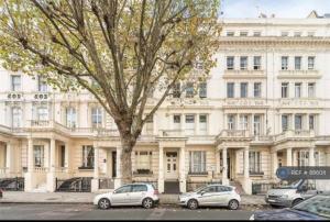 dois carros estacionados em frente a um grande edifício branco em [Bayswater-Hyde park] London Studio Apartment em Londres