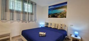 ein Schlafzimmer mit einem blauen Bett und einem Gemälde an der Wand in der Unterkunft La casa al mare, Pittulongu in Olbia