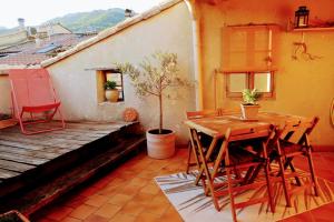 a patio with a wooden table and chairs on a house at La Terrasse d'Oléa, au coeur du village in Buis-les-Baronnies