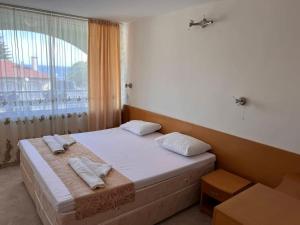 a bed in a room with a large window at Хотел Диамант Hotel Diamond in Balchik