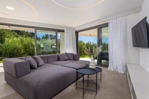 a living room with a gray couch and a large window at HADRIE LUXURY RESORT AND VILLAS Krk in Krk