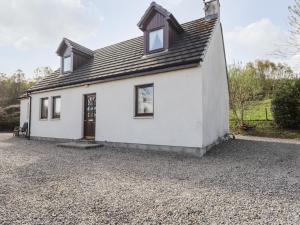 a white house on a gravel driveway at Balnabodach in Inverness