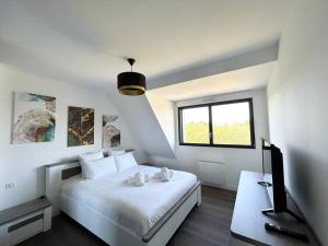 - une chambre blanche avec un lit et une télévision dans l'établissement Belle maison rénovée à la plage, à Fouesnant
