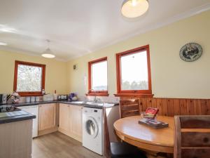a kitchen with a washing machine and a wooden table at Balnabodach in Inverness