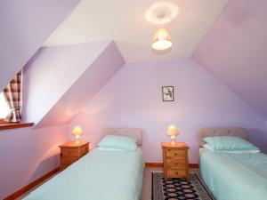 a attic bedroom with two beds and two lamps at Balnabodach in Inverness