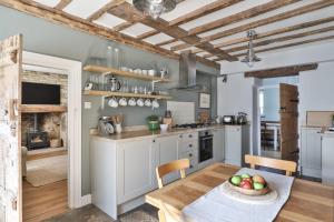 - une cuisine avec des placards blancs et une table avec un bol de fruits dans l'établissement Coombers Mead Cottage, à Tetbury