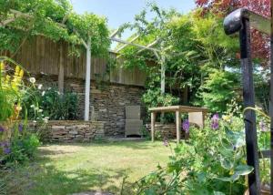a garden with a stone wall and a table at Coombers Mead Cottage in Tetbury +30 photos