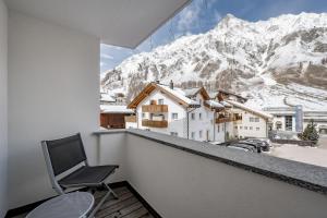 a chair on a balcony with a view of a mountain at Hotel Nevada in Samnaun