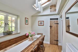 Coombers Mead Cottage في تيتبري: غرفة طعام مع طاولة وكراسي ونوافذ