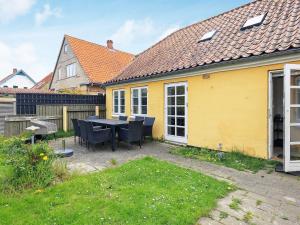 ein gelbes Haus mit einem Tisch und Stühlen im Hof in der Unterkunft 11 person holiday home in r sk bing in Ærøskøbing