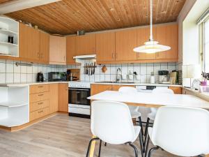 a kitchen with white chairs and a wooden ceiling at 11 person holiday home in r sk bing in Ærøskøbing