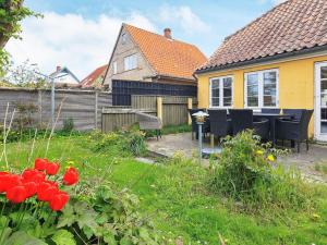 un giardino con fiori rossi e una casa gialla di 11 person holiday home in r sk bing a Ærøskøbing