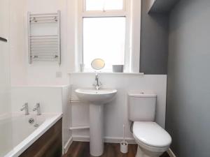 a bathroom with a sink and a toilet and a window at Magenta Melodies, 5 Bedroom House in Blackpool