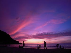 a group of people standing on the beach at sunset at Palita Lodge - SHA Plus in Haad Rin