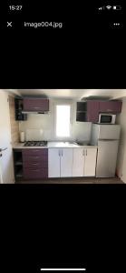 a kitchen with white and purple cabinets and a window at Mobile Home Pinija in Jezera