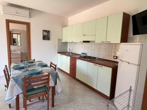 cocina con mesa y cocina con armarios blancos en Case Vacanza Calabria Ionica, en Cropani
