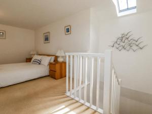 a white bedroom with a bed and a white staircase at The Mill in Tintagel