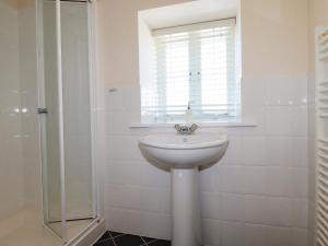 baño blanco con lavabo y ventana en The Mill en Tintagel