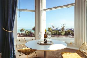 a table with a bottle of wine on it in front of a window at Pier Reflections - seafront apartment in Eastbourne