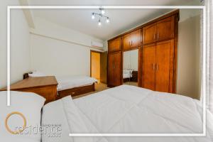a bedroom with a white bed and wooden cabinets at Luxury apartments in Mivida new cairo in New cairo