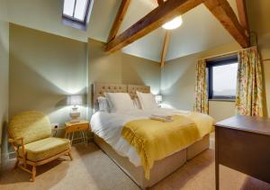 a bedroom with a bed and a chair and a window at The Foldyard in Holme upon Spalding Moor