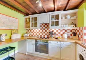 a kitchen with white cabinets and a checkered wall at The Cottage in Thwaite