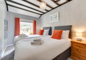 2 bedden in een slaapkamer met oranje en witte kussens bij The Cottage in Thwaite