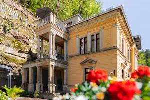una antigua casa amarilla con balcón y flores en Villa Emma, Wellness & Ayurveda, en Bad Schandau
