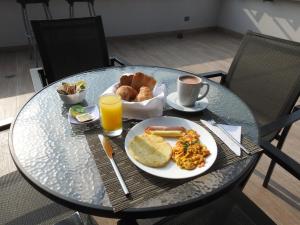 a glass table with a plate of breakfast foods and a cup of coffee at Park V in Cali