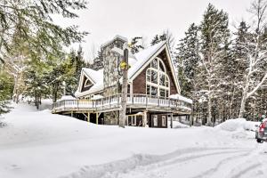 a log cabin in the snow with a car parked in front at Waitsfield Vacation Rental with Private Hot Tub in Waitsfield