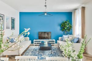 a living room with blue walls and white furniture at Free Private Parking - 15mn Paris - 5mn Walk Train Station - All equipped - Terrace - Garden - Stade de France - Casino d'Enghien - Hippodrome, Université in Épinay-sur-Seine