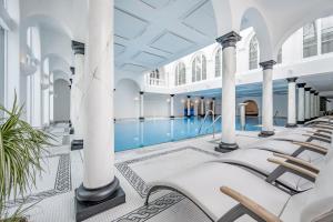 una piscina en un edificio con columnas y sillas blancas en Relais & Châteaux Chasa Montana, en Samnaun