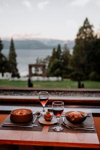 uma mesa com dois copos de vinho e comida em Basia Hotel & Sushi em San Carlos de Bariloche