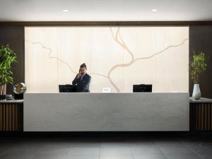 AC Hotel by Marriott Dayton في دايتون: رجل يتحدث على الهاتف الخلوي في مكتب الاستقبال