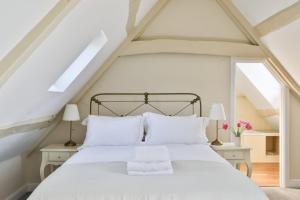 a bedroom with a white bed with white pillows at Coombers Mead Cottage in Tetbury