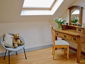 a teddy bear sitting in a chair next to a desk at Field View in Cynghordy