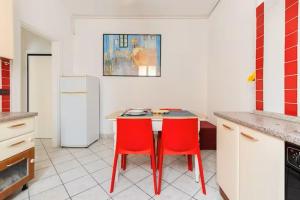 uma cozinha com uma mesa e duas cadeiras vermelhas em Appartamento Tipico Veneziano em Veneza