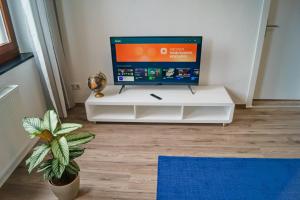un televisor en un puesto blanco en una habitación con una planta en Charmante & Gemütliche Wohnung en Solingen