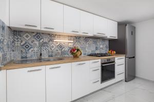 a kitchen with white cabinets and a sink at House Bajota with terrace and sea view in Beli