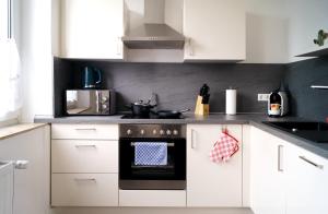 una cocina con armarios blancos y horno negro en Charmante & Gemütliche Wohnung en Solingen