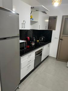 una cocina con electrodomésticos blancos y encimeras negras en Appartement Irena neuf à 5 min de la plage, en Saidia 