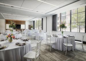 een kamer met witte tafels en stoelen met bloemen erop bij AC Hotel by Marriott Dayton in Dayton