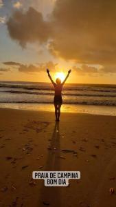 a person walking on the beach with the sun in the background at casa de praia a beira mar in Campina