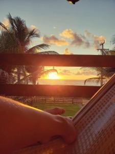 a person sitting in a hammock watching the sunset at casa de praia a beira mar in Campina